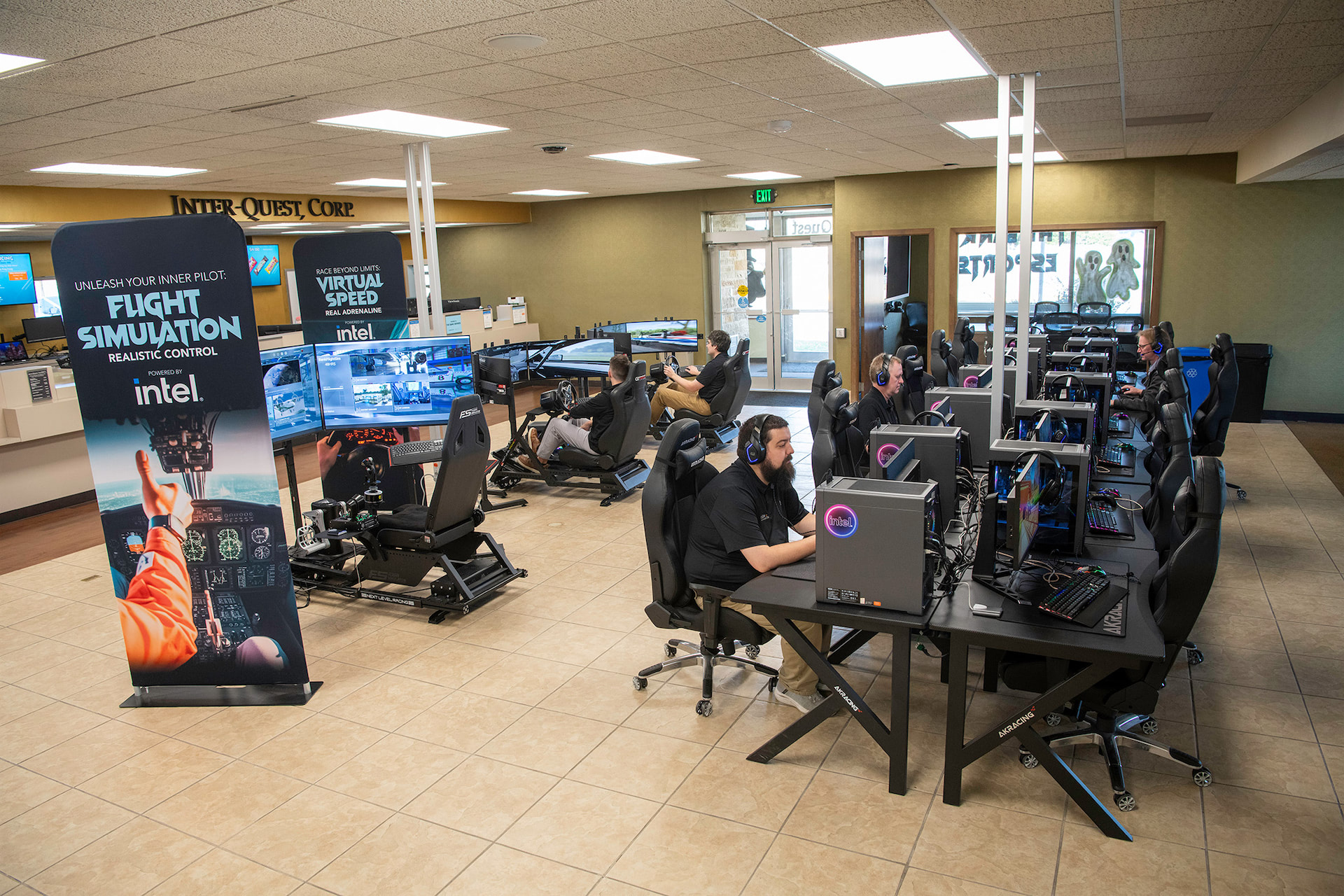 Gaming PCs and racing simulators setup with people playing on them